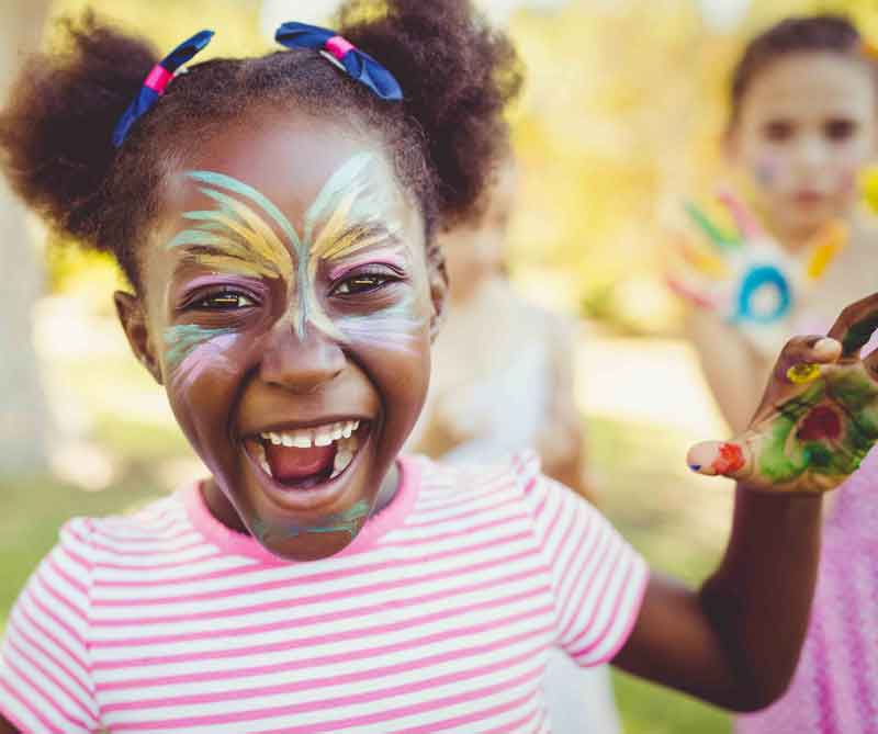 lachend meisje met grote roze vlinder op gezicht geschminkt