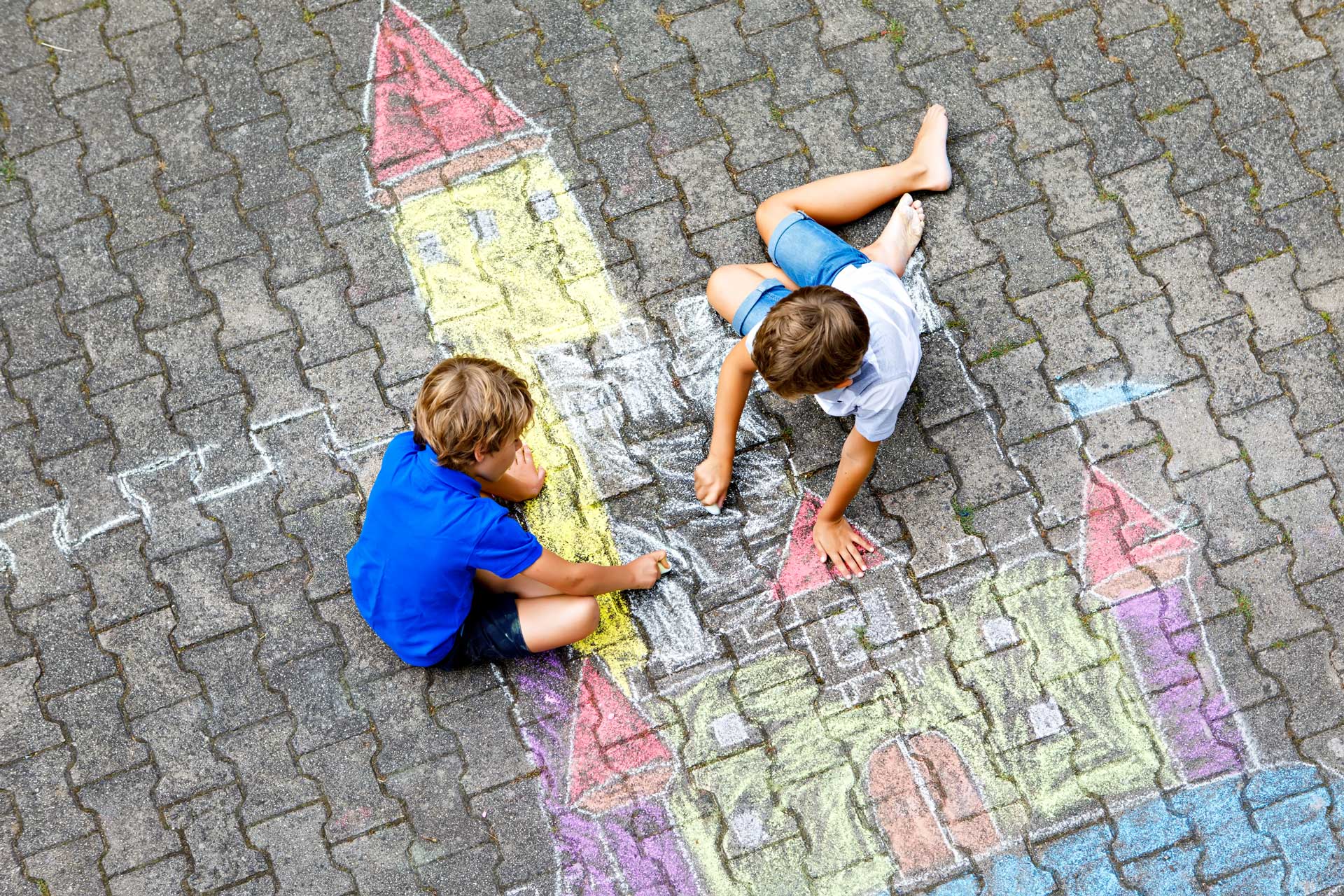 kinderen spelen met stoepkrijt en tekenen een kleurrijk kasteel