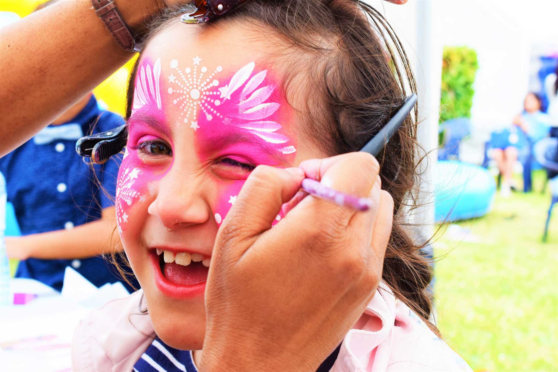 meisje krijgt een grote roze vlinder op haar gezicht geschminkt